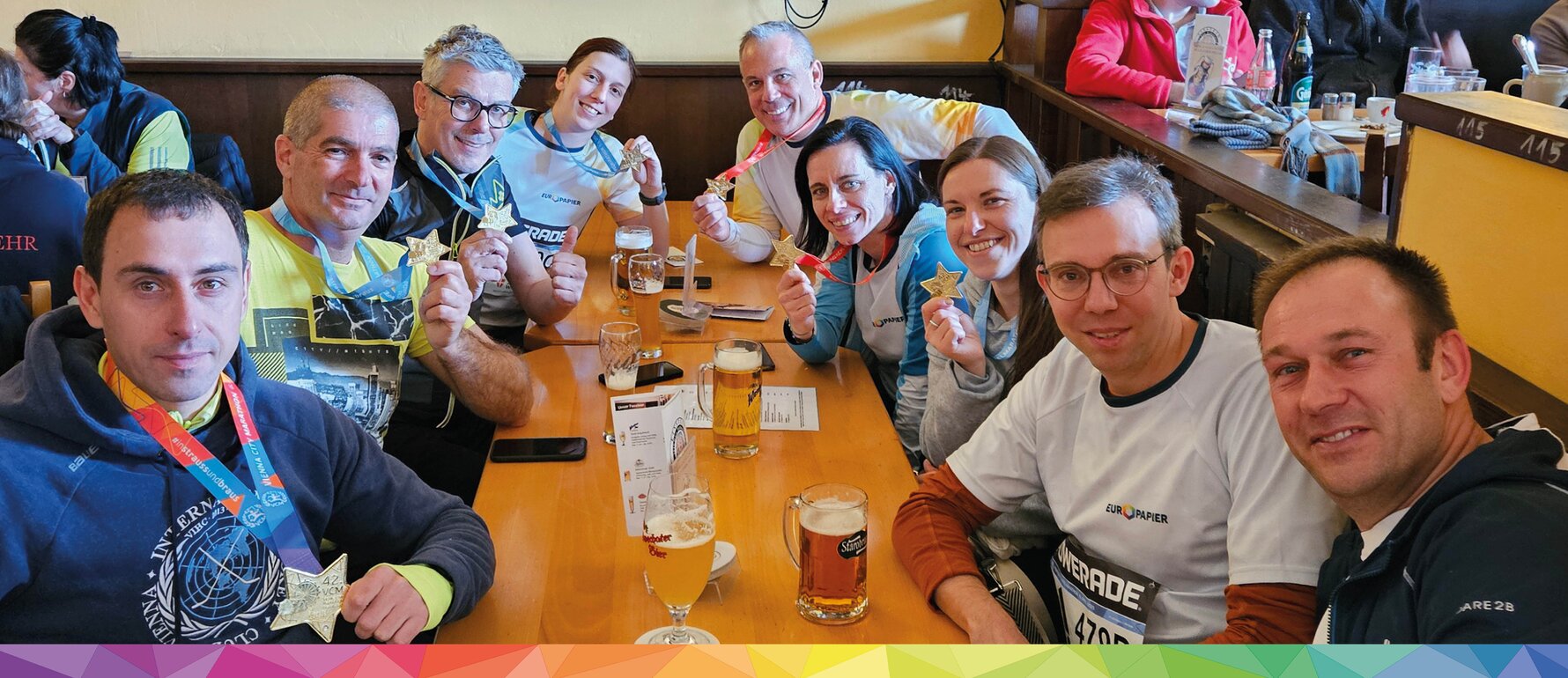 Neun VCM2025 Teilnehmer sitzen beim Tisch und zeigen ihre Medaillen